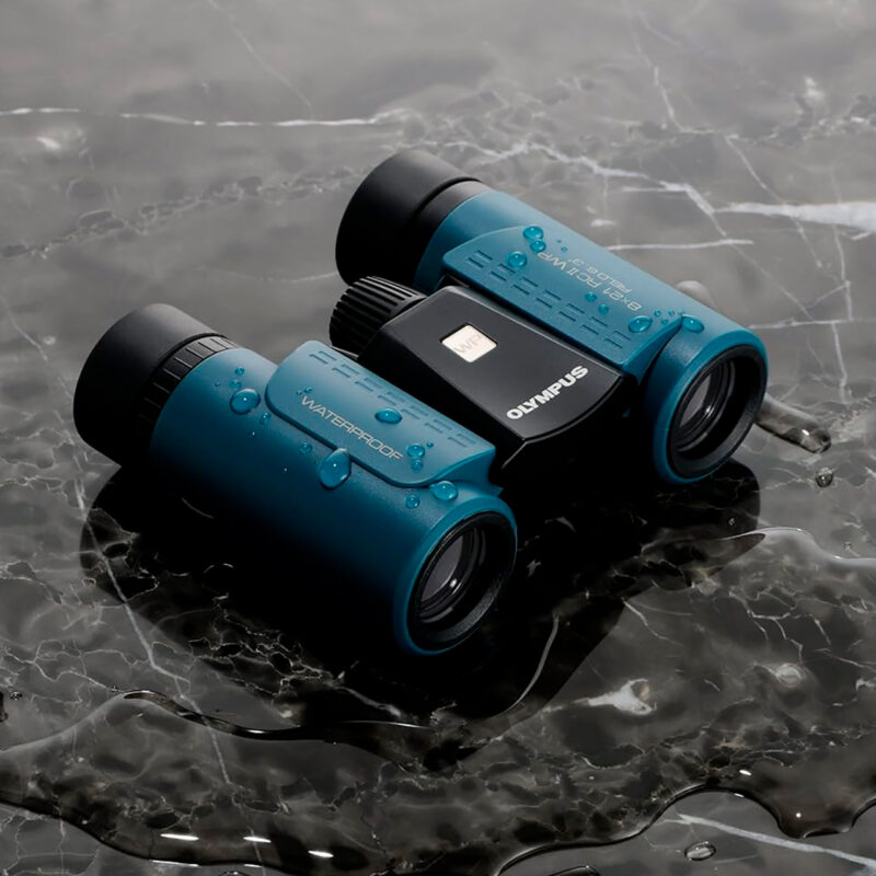 Binoculares Olympus de 8x21, impermeables, con diseño compacto y lentes antideslumbrantes sobre fondo de mármol húmedo.