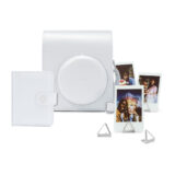 Cámara Instax, funda blanca, álbum fotográfico y soportes para fotos instantáneas en una composición elegante.