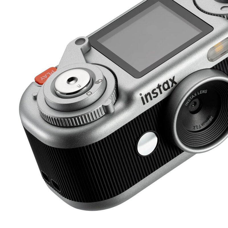fuj170518-7-4f5 Cámara instantánea Fujifilm Instax con diseño moderno, lente de 28 mm y botón de captura en color plata.
